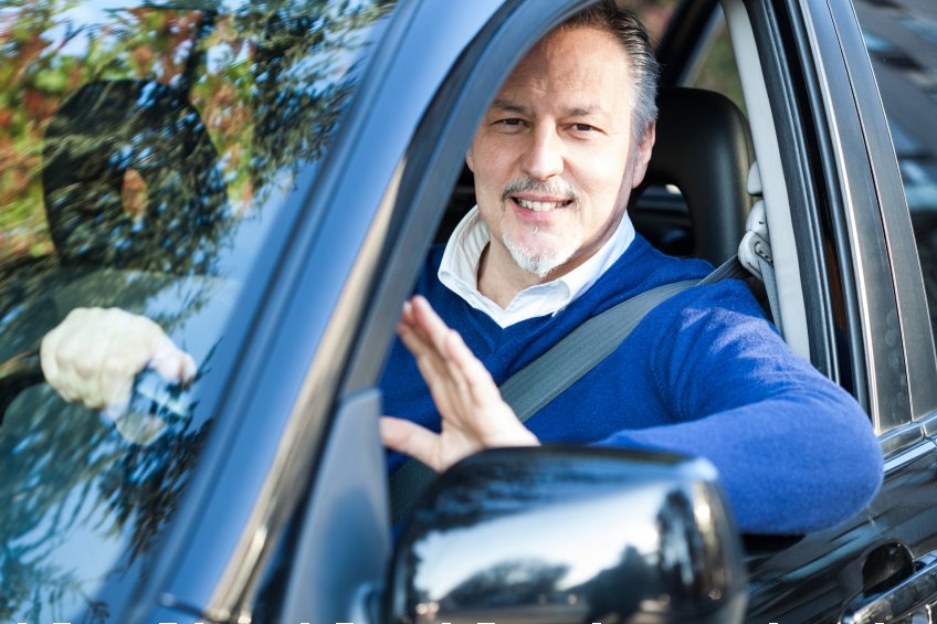 man waving from car driver's seat