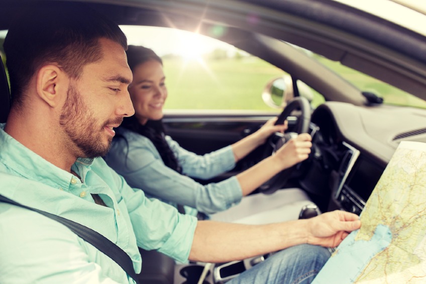 happy man and woman with road map driving in car